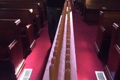 John and Alex carry a toe board to be temporarily stored in the pews.